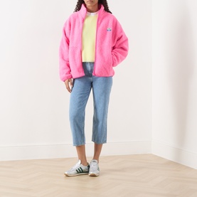 Model wearing AMERICAN VINTAGE Vitow Knitted Sweater in Citronnier Chine yellow, styled with pink fleece jacket, cropped blue jeans and green