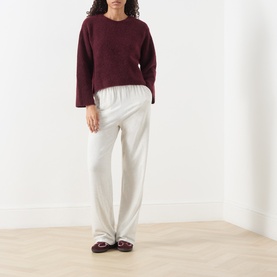 Model wearing American Vintage Vitow Knitted Sweater in Grenat Chine with cream wide-leg trousers and burgundy loafers