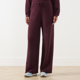 Model wearing American Vintage Atubay Drawstring Wide Leg Sweatpants in Lie de Vin, wide leg fit with elasticated waist, styled with light blue