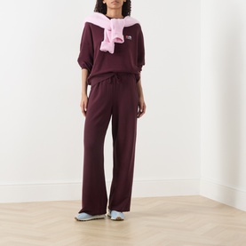 Model wearing American Vintage Atubay Drawstring Wide Leg Sweatpants in lie de vin, styled with matching burgundy sweatshirt and pink scarf.