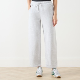 Model wearing American Vintage Sweat Bottom in Gris Chin&eacute;, wide-leg cut with drawstring waist, styled with green and white trainers.