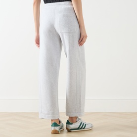 Model wearing American Vintage Sweat Bottom in Gris Chine, wide-leg fit with elasticated waist, styled with green stripe trainers.