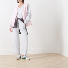 Model wearing American Vintage Gris Chine sweat bottoms, styled with a pink jacket, striped top, and green adidas trainers.