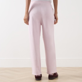 Model wearing American Vintage Sweat Bottom in Petale Vintage, wide-leg cotton style, rear view, styled with burgundy loafers.