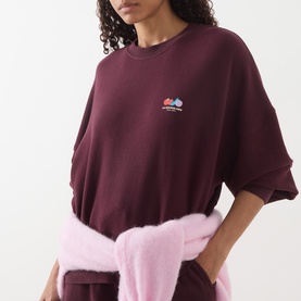 Model wearing American Vintage Atubay Logo Sweatshirt in Lie de Vin, crew neck with chest logo, styled with pink fluffy cardigan tied at waist
