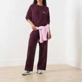 Model wearing American Vintage Atubay Logo Sweatshirt in lie de vin, crew neck, with matching wide-leg trousers and pink jacket tied at waist.