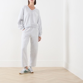 Model wearing American Vintage Gris Chine sweat top with matching grey joggers and green and white trainers.
