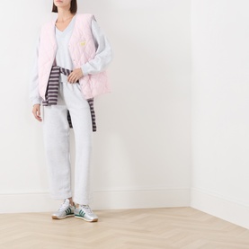 Model wearing American Vintage Sweat Top in Gris Chine, styled with a pink gilet, striped tee, and green trainers.