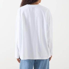 Model wearing AMERICAN VINTAGE Gixy Logo Long-Sleeved Top in white, crew neck, dropped shoulders, long sleeves, styled with light blue jeans.