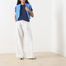 Model wearing American Vintage Apoly Solid T-Shirt in Night Star, styled with white wide-leg trousers and a blue vest top.