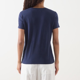 Model wearing American Vintage Apoly Solid T-Shirt in Night Star, crew neck, short sleeves, back view, styled with white wide-leg trousers