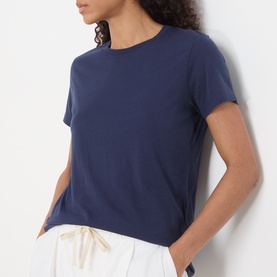 Model wearing American Vintage Apoly Solid T-Shirt in Night Star. Crew neck, short sleeves, styled with white drawstring trousers.