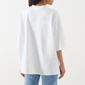Model wearing American Vintage Afoma Oversized T-Shirt in white, back view, with blue jeans. Round neck, short sleeves, straight hem.