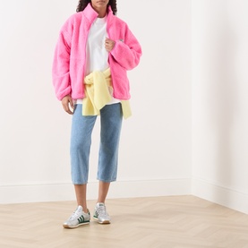 Model wearing American Vintage Afoma Oversized White T-Shirt, styled with pink faux fur jacket, light blue cropped jeans and white trainers.