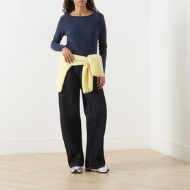 Model wearing AMERICAN VINTAGE Sonoma Long-Sleeved Slub T-Shirt in navy blue vintage, styled with black wide-leg trousers and yellow knitwear tied at