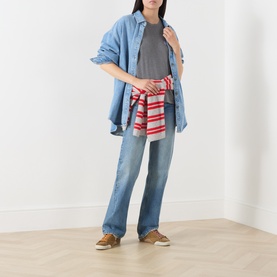 Model wearing American Vintage granite chin&eacute; cotton T-shirt with denim shirt, striped top tied at waist and light-wash flared jeans