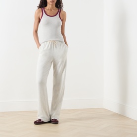 Model wearing AMERICAN VINTAGE Cribay Contrast-Trim Tank Top in Gris Chine with purple trim, styled with cream wide-leg trousers and burgundy loafers.