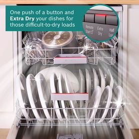 Integrated dishwasher interior loaded with white dishes and pots, highlighting Extra Dry function button on control panel