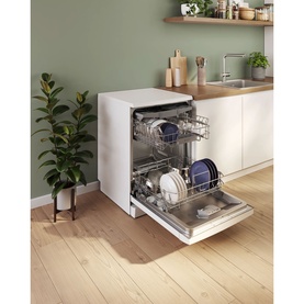 Freestanding white dishwasher with open door revealing two loaded rack levels, styled in a modern kitchen setting with wood flooring