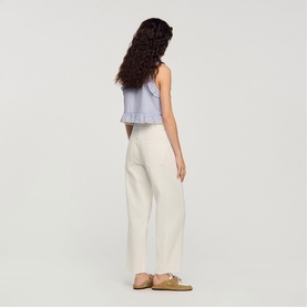 Model wearing Sandro Womens French Dress in clear, back view, styled with a light blue crop top and tan sandals