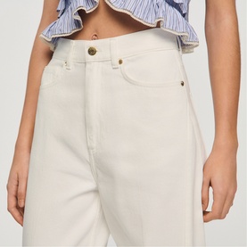 Model wearing Sandro clear wide-leg jeans with gold-tone button detail, styled with a blue striped ruffle crop top