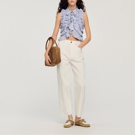 Model wearing Sandro Womens French Dress in clear, styled with cream trousers, carrying a tan bag and wearing gold loafers.
