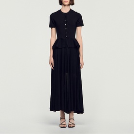 Model wearing Sandro Peplum Flared Knitted Dress in black, maxi length with peplum waist, short sleeves, button fastening, and flared skirt.