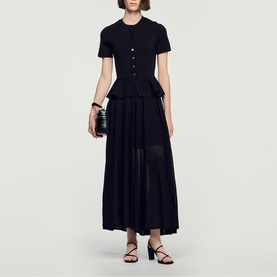Model wearing Sandro Peplum Flared Knitted Dress in black, maxi length with peplum waist, short sleeves