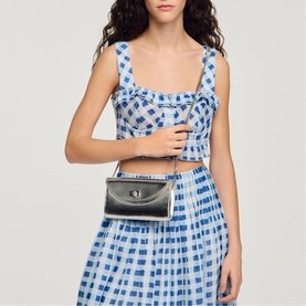 Model carrying Sandro black structured crossbody bag with silver-tone hardware, styled with a blue gingham crop top and midi skirt