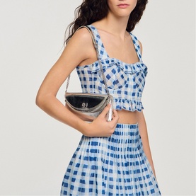 Model carrying Sandro black small crossbody bag with silver-tone hardware, styled with blue gingham crop top and midi skirt