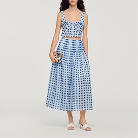 Model wearing Sandro blue gingham check crop top and midi skirt co-ord, styled with white heeled mules and silver clutch bag.