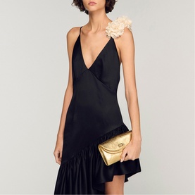 Model carrying Sandro yellow quilted clutch bag with gold hardware, styled with black slip dress featuring floral shoulder detail