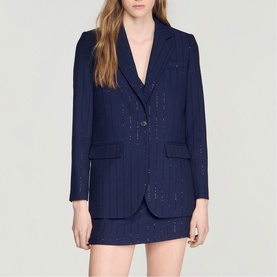 Model wearing Sandro dark navy pinstripe blazer with subtle sequin detail, styled with matching mini skirt