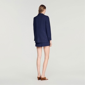 Model wearing Sandro dark navy pinstripe blazer and matching mini skirt, shown from behind, styled with brown mule heels