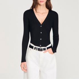 Model wearing Sandro black ribbed V-neck cardigan with button front, styled with white jeans and a white belt.