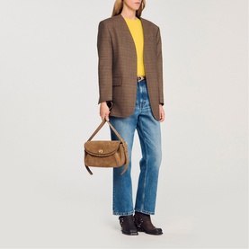 Model carrying Sandro Le Mambo Suede Shoulder Bag in clear tan, with double flap and swivel clasp, styled with blazer and jeans.