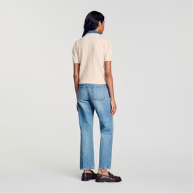 Model wearing Sandro top in clear, styled with blue straight-leg jeans and dark loafers, rear view