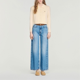 Model wearing Sandro cropped polo top in clear, styled with wide-leg blue jeans and tan loafers