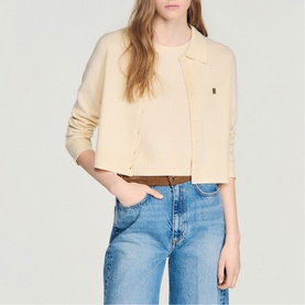 Model wearing Sandro cream cropped cardigan with button front, styled with light wash jeans and brown belt
