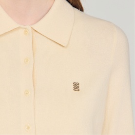 Model wearing Sandro cream knit polo shirt with point collar and gold monogram logo embroidery at chest