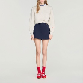Model wearing Sandro Womens French Dress in navy blue mini skirt style, styled with cream sweatshirt and red shoes