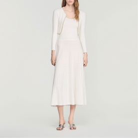 Model wearing Sandro Womens French Dress in clear white, featuring pleated midi skirt and cropped knit cardigan, styled with metallic sandals.