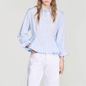 Model wearing Sandro sky blue striped peplum shirt with long cuffed sleeves, styled with white trousers.