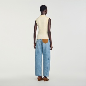 Model wearing a cream sleeveless ribbed knit top, styled with light blue wide-leg jeans and brown shoes, back view