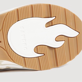 Sandro trainer sole detail showing white flame-shaped insert on tan ribbed rubber outsole with embossed Sandro branding.
