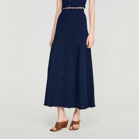 Model wearing Sandro navy blue maxi skirt with frayed hem, styled with a white top and tan heeled mules