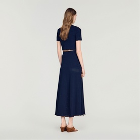 Model wearing Sandro Womens French Dress in navy blue, short sleeves, maxi length, styled with a tan belt and brown mules, rear view.