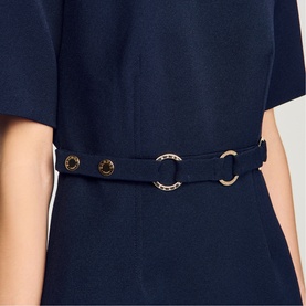 Model wearing Sandro Womens French Dress in navy blue, close-up of gold ring belt detail and short sleeve.