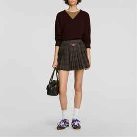 Model wearing Sandro dark grey tartan pleated mini skirt, styled with burgundy knit, white socks, purple trainers, carrying black bag