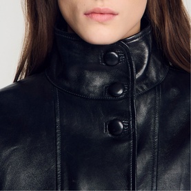 Model wearing Sandro black leather jacket, close-up of high funnel neck collar with double button fastening detail